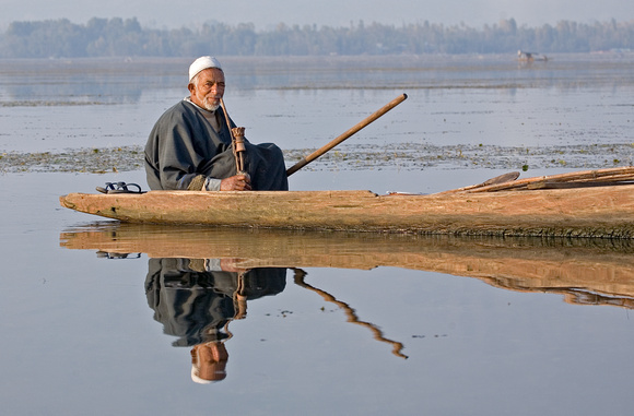 Man smoking hookah pipe in dugout boat, Dal Lake, Kashmir, India