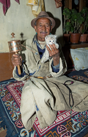 Ladakhi man with prayer wheel and kitten, Ladakh, India