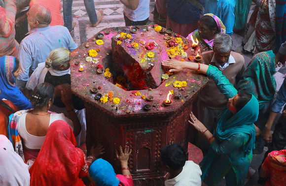 Woman touching holy shrine with rock, Holi festival, Vrindavan, India
